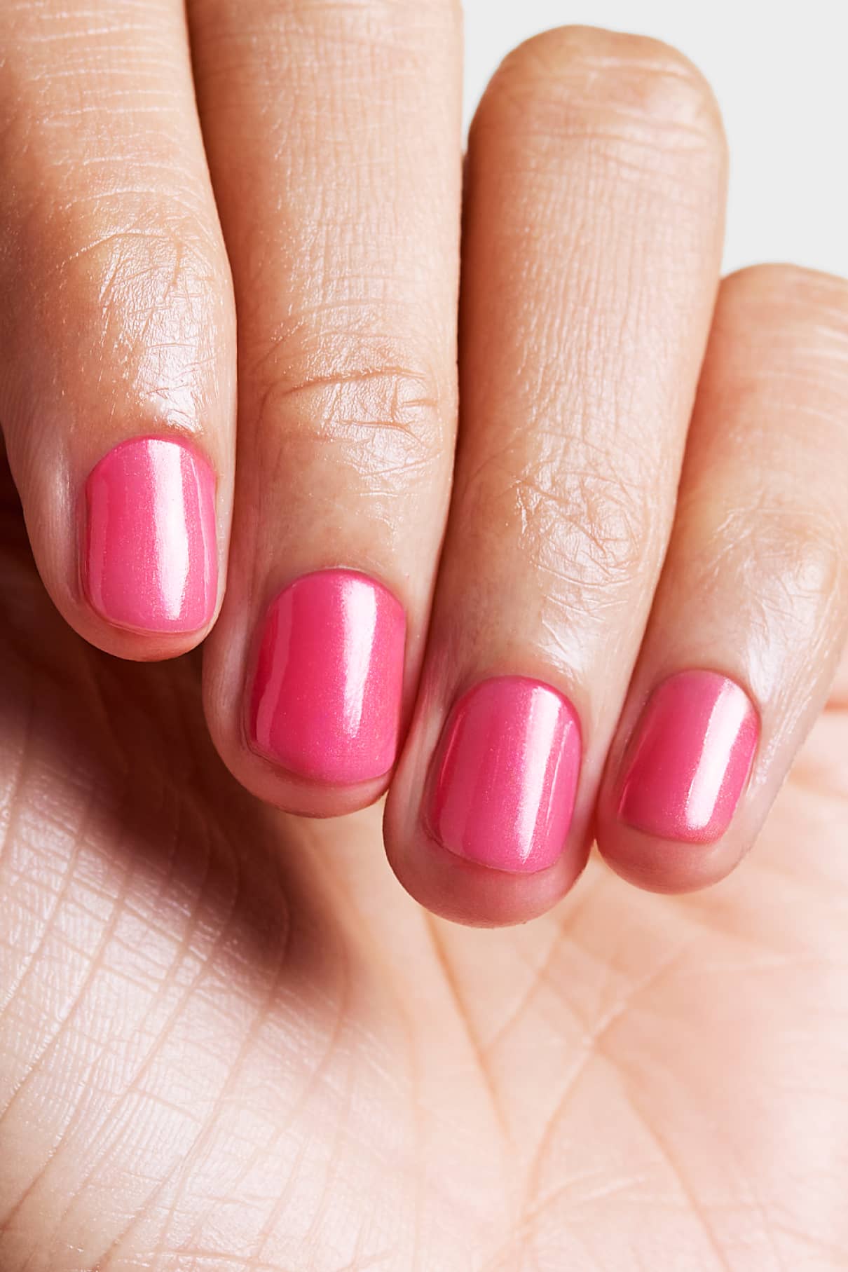 Nahaufnahme einer Hand mit vier Fingern, deren Nägel mit der rosafarbenen Skinified Nail Tint 05, angereichert mit Hyaluronsäure, lackiert sind.