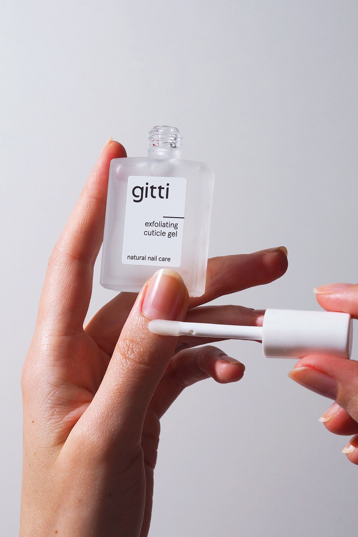 Eine Person hält eine Flasche Nail Recovery Starter Treatment in der Hand, schraubt den Applikatorpinsel ab und beginnt mit ihrer Reparaturroutine für stärkere Nägel.