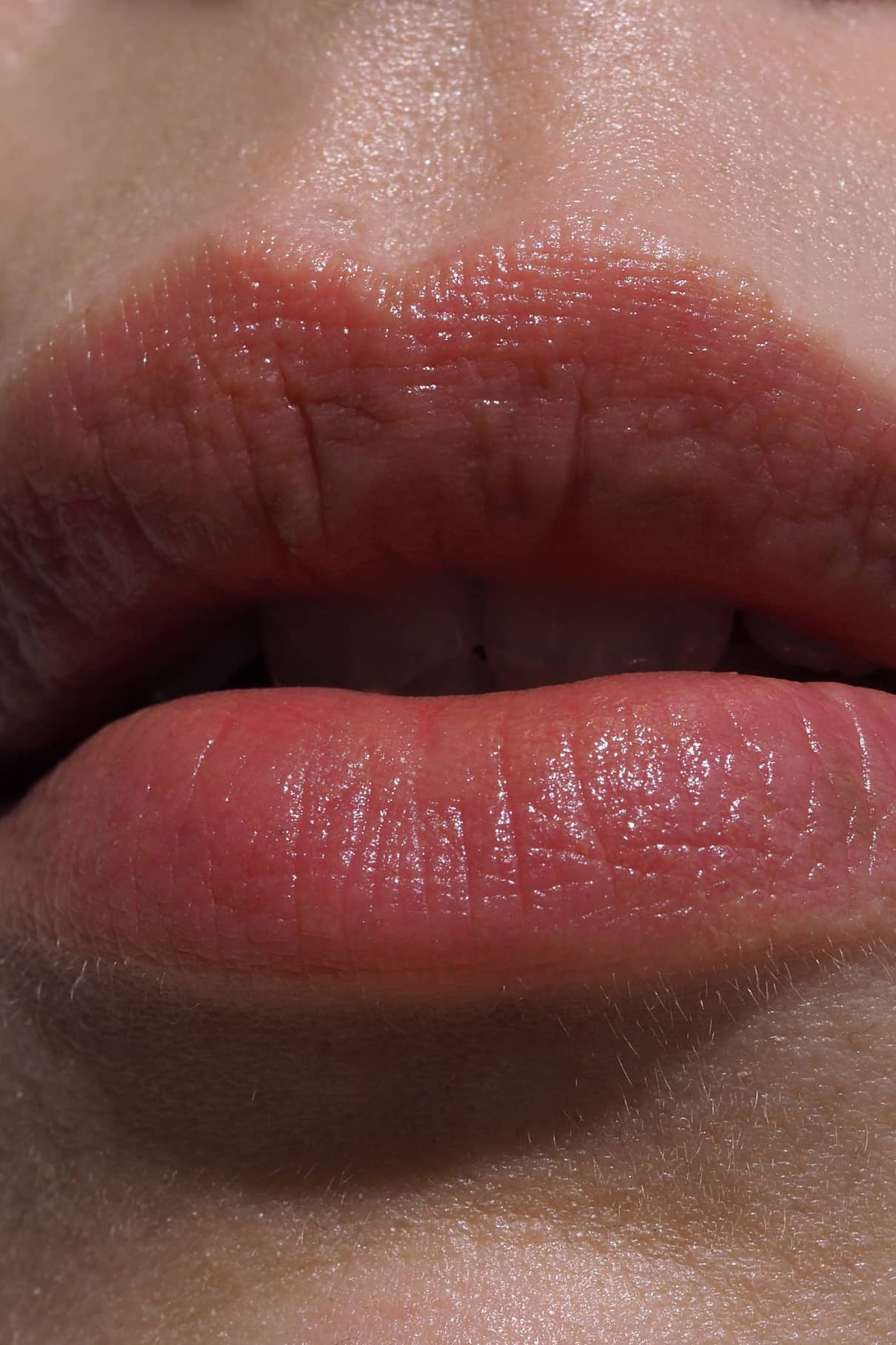 Nahaufnahme der natürlichen Lippen mit Lip Sync Refill Nr. 01, leicht gescheitelt, um warme braune Hauttöne mit rötlichem Unterton zu betonen und die natürliche Hautstruktur und feine Gesichtsbehaarung hervorzuheben.