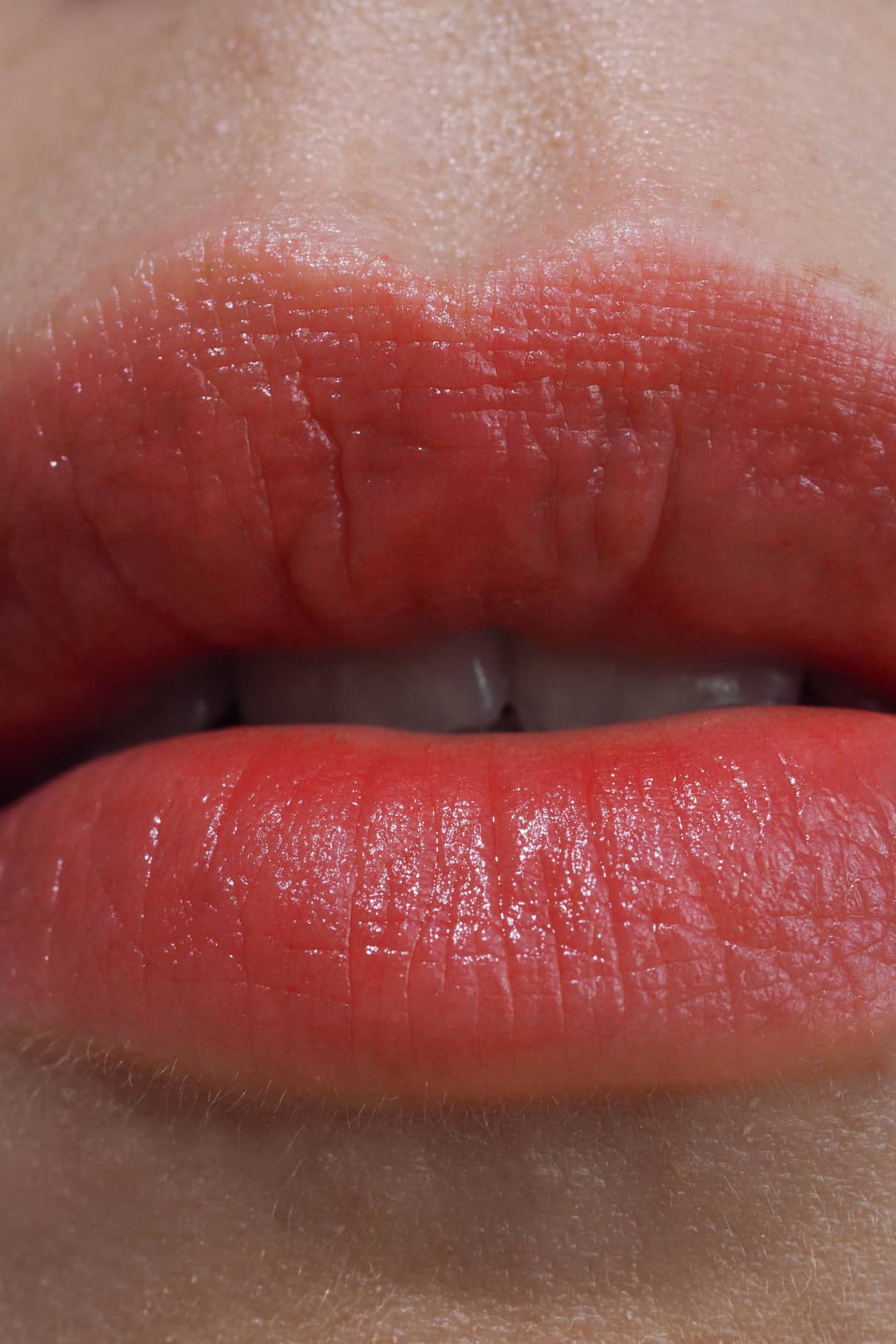 Nahaufnahme der Lippen einer Person, die Lip Sync Refill Nr. 03 in zartem rosa Korall-Ton, mit sichtbarer Lippentextur und einem Hauch von Zähnen zwischen leicht gescheitelten Lippen - ideal für neutrale Hauttypen.