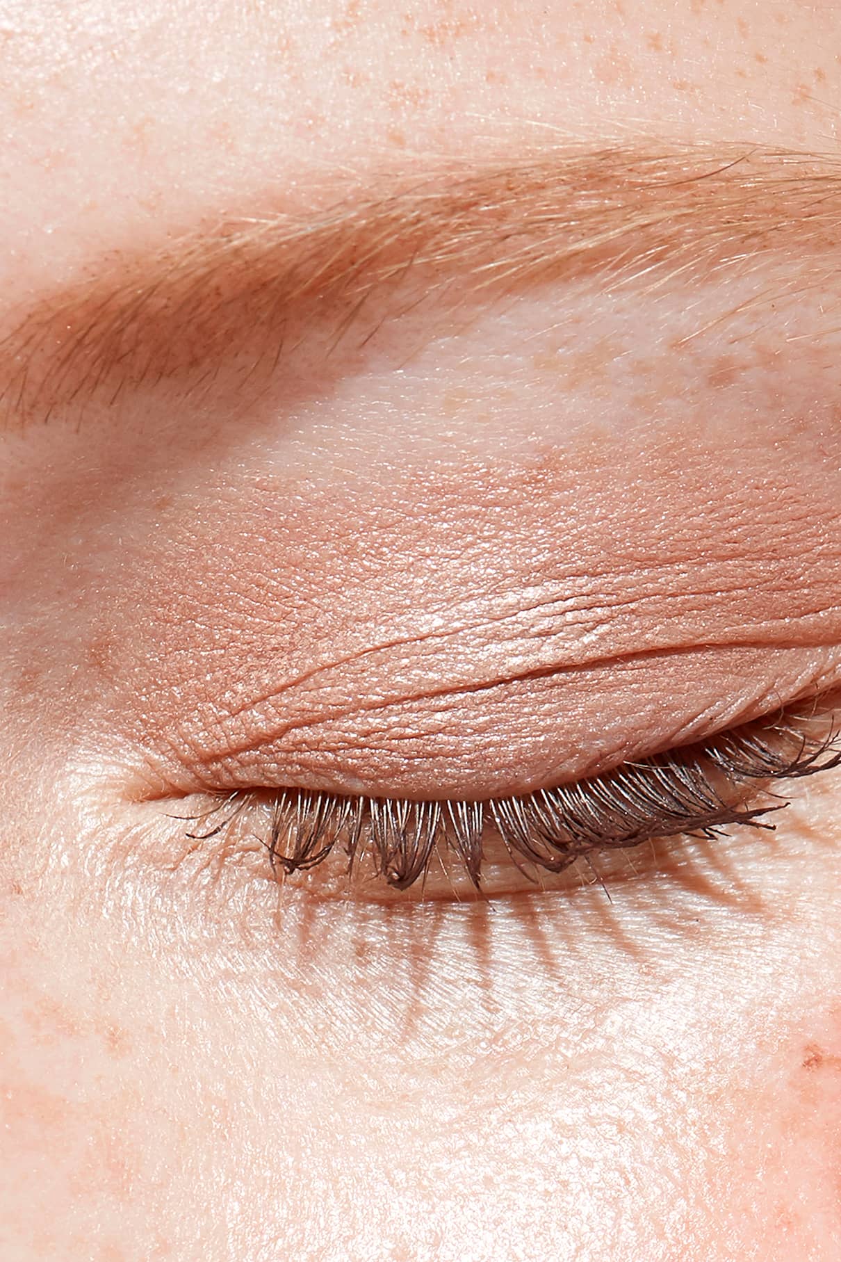 Nahaufnahme des geschlossenen Auges einer Person mit hellbraunem Lidschatten des Eye Colour Set, sichtbarer Augenbraue, getuschten Wimpern und Sommersprossen auf heller Haut.
