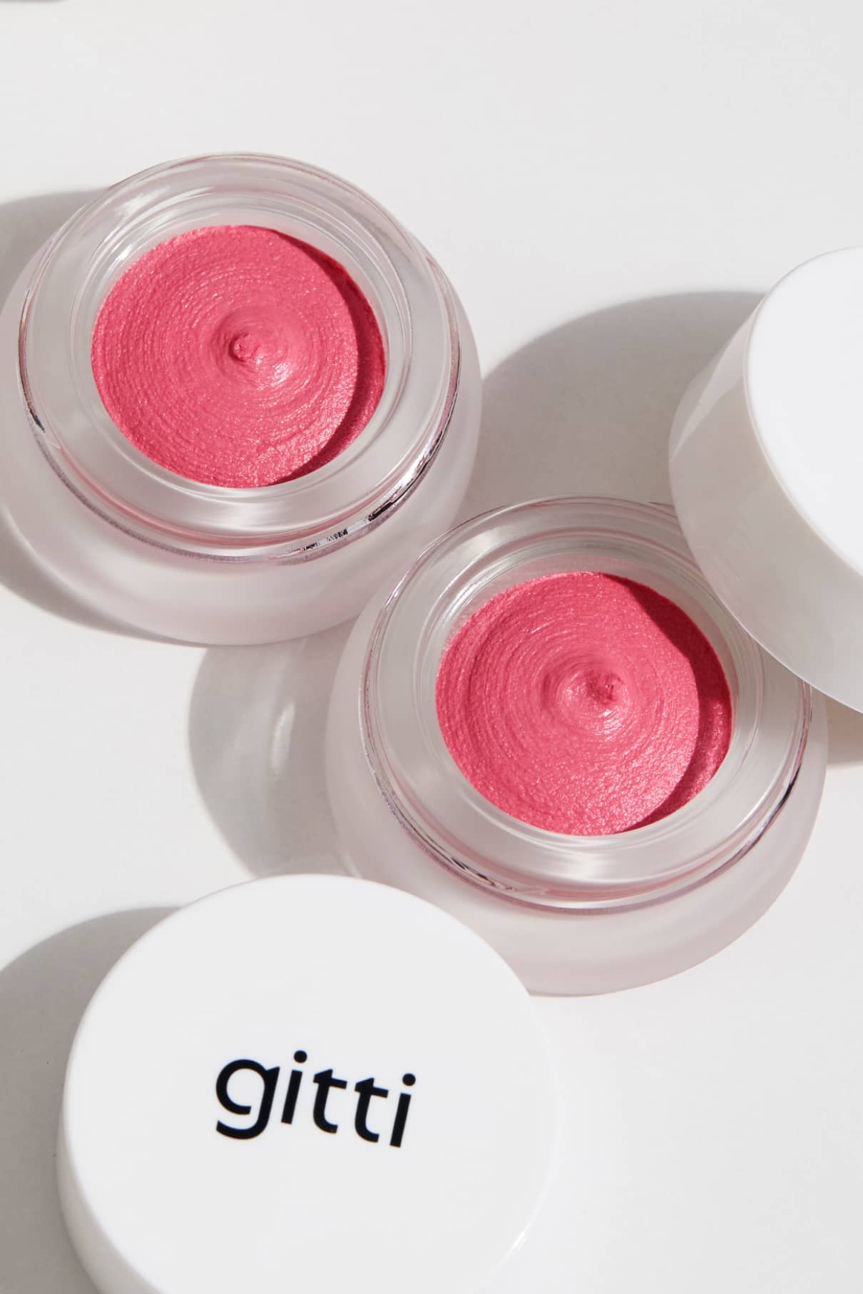 Zwei geöffnete Gläser Velvet Cheeks Nr. 05 rosa Mousse-Blush mit weißen Deckeln, einer davon mit dem Markennamen "gitti". Die silikonfreie Formel verleiht einen sanften, natürlichen Schimmer.