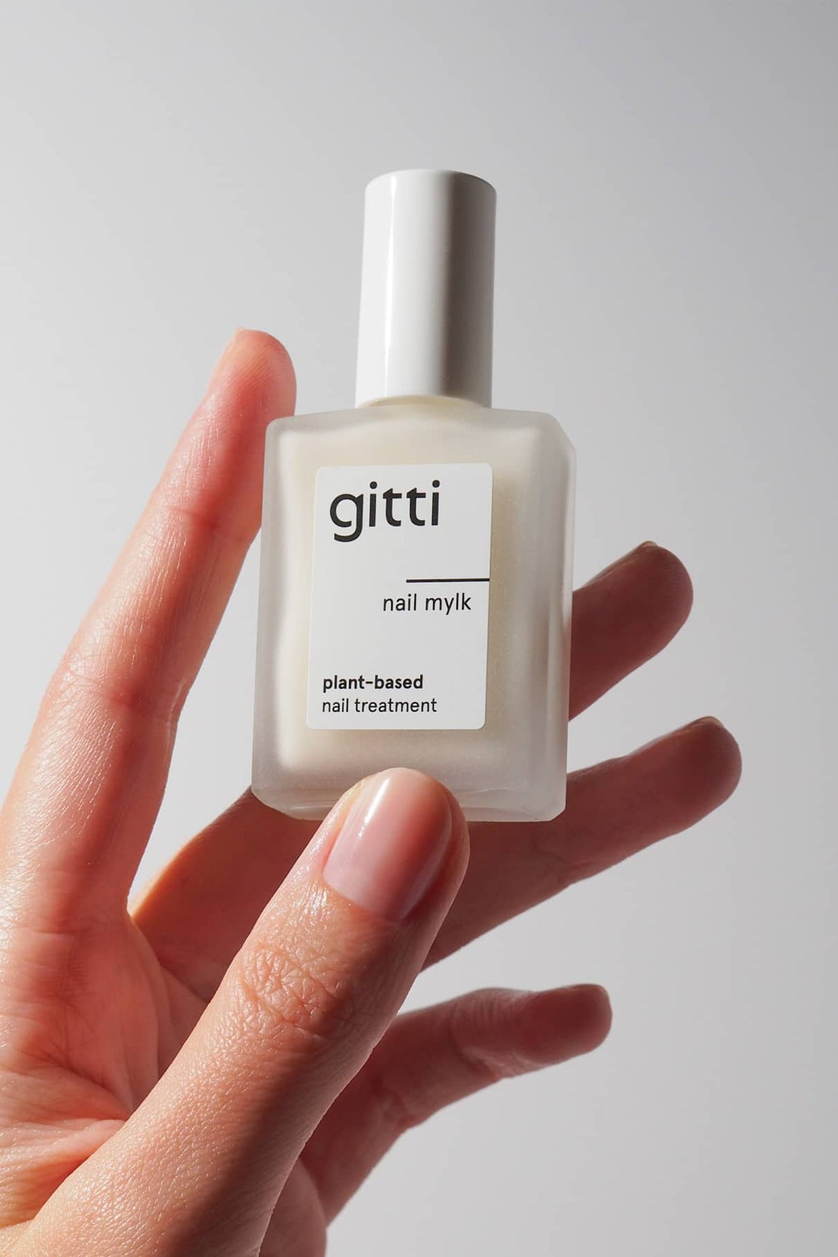 Hand hält eine Flasche Nail Mylk Pflegelack