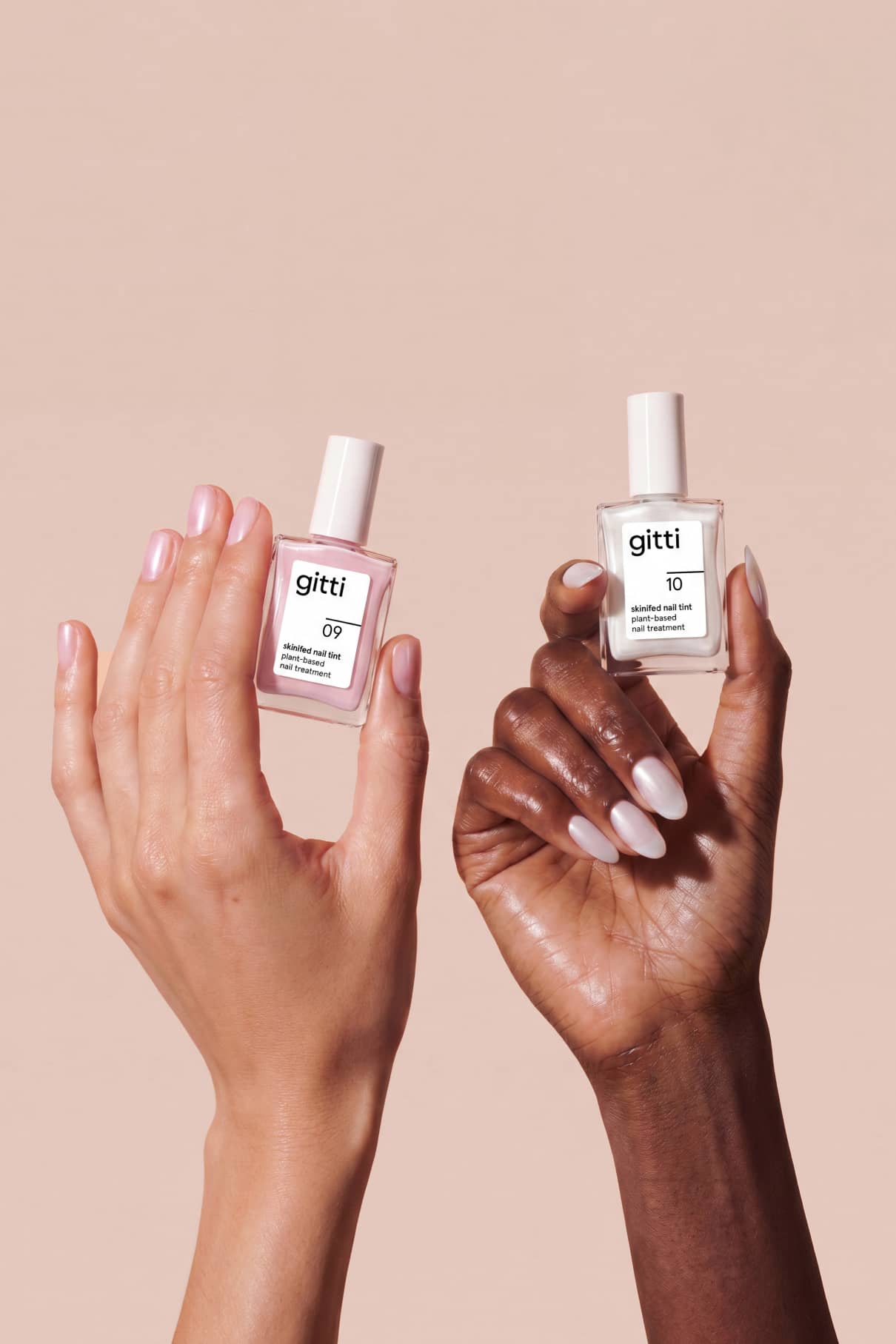 Zwei Hände mit manikürten Nägeln halten das Treatment Duo, ein Set mit 15 ml Gitti-Nagelpflege in Glasflaschen, vor einem neutralen beigen Hintergrund.