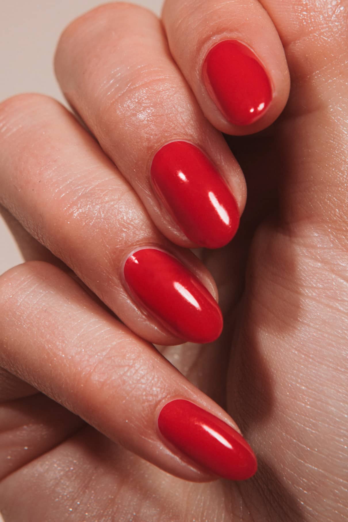 Eine Nahaufnahme einer Hand mit gepflegten Nägeln, lackiert mit „Gitti x PETA“-Nagellack in „leuchtendes Rot“ mit orangen Untertönen – für einen auffälligen, lebendigen Look.