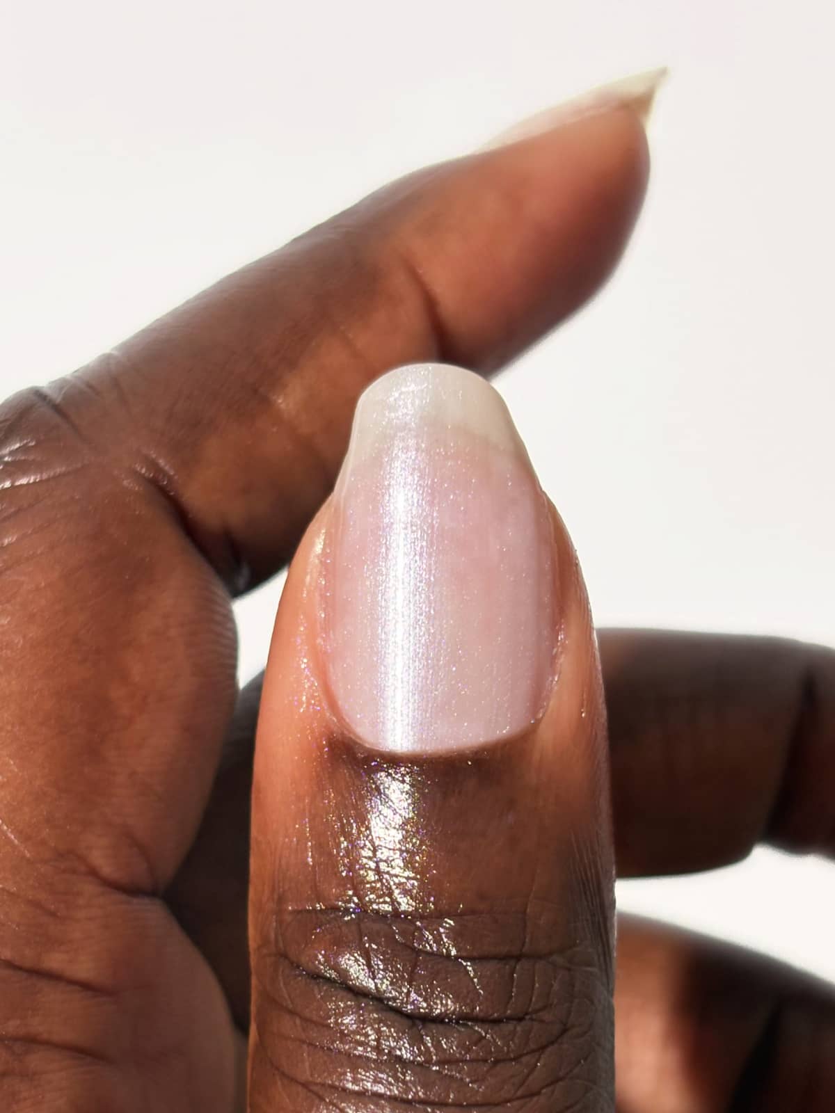 Eine Nahaufnahme des Daumens einer Person, die einen natürlichen, gesunden Fingernagel mit glänzender, klarer Oberfläche und dem zarten Rosaton von „Gitti Nr. 059“ zeigt, der für einen strahlenden Look sorgt.