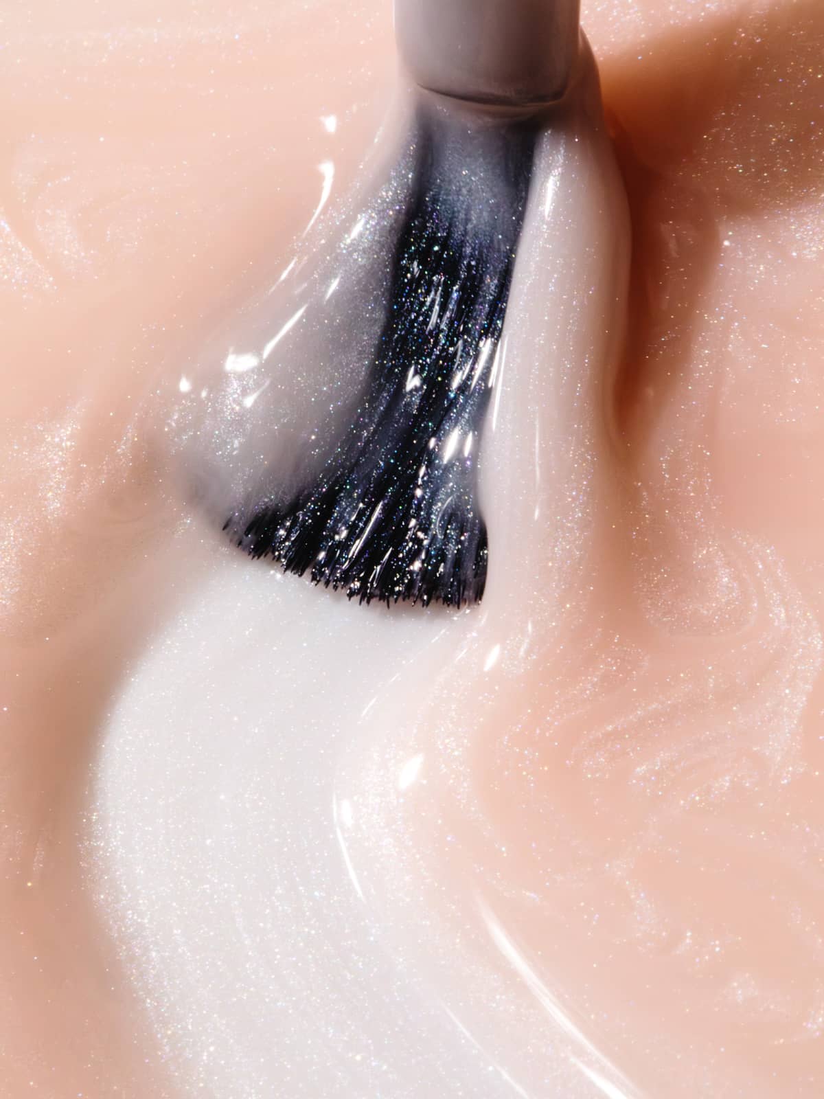 Nahaufnahme eines Pinsels, der „Gitti Nr. 059“, einen schimmernden, blassrosa Nagellack, mit sanften Strichen auf eine glänzende Oberfläche aufträgt, um einen strahlenderen Look zu erzielen.