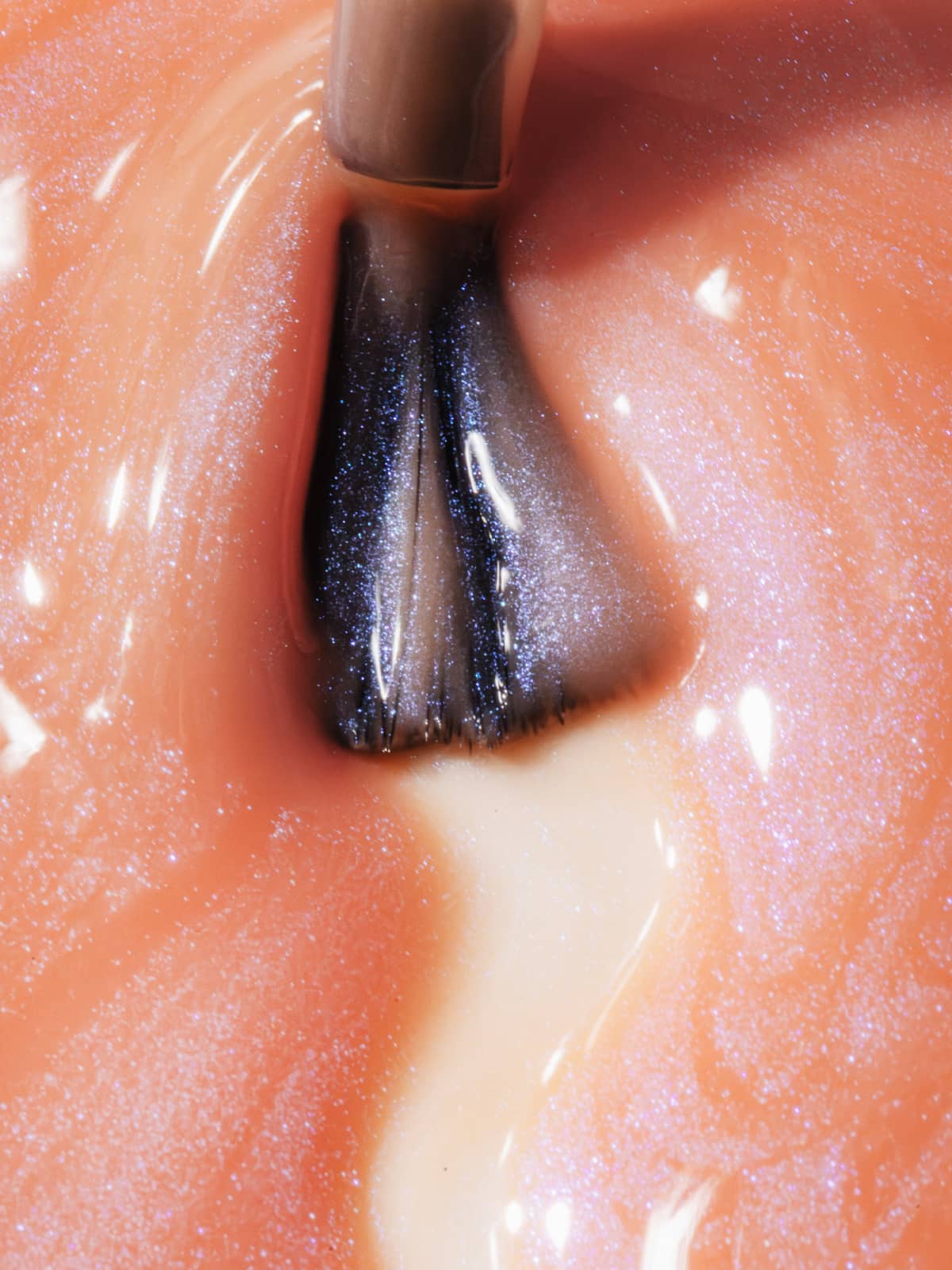Eine Nahaufnahme eines Nagellackpinsels, der den Farbton „Gitti Nr. 060“ – einen schimmernden, transparenten Apricotton-Farbton – auf einen Fingernagel aufträgt und dabei einen kühlen Schimmer und einen frischen Glanz hinterlässt.