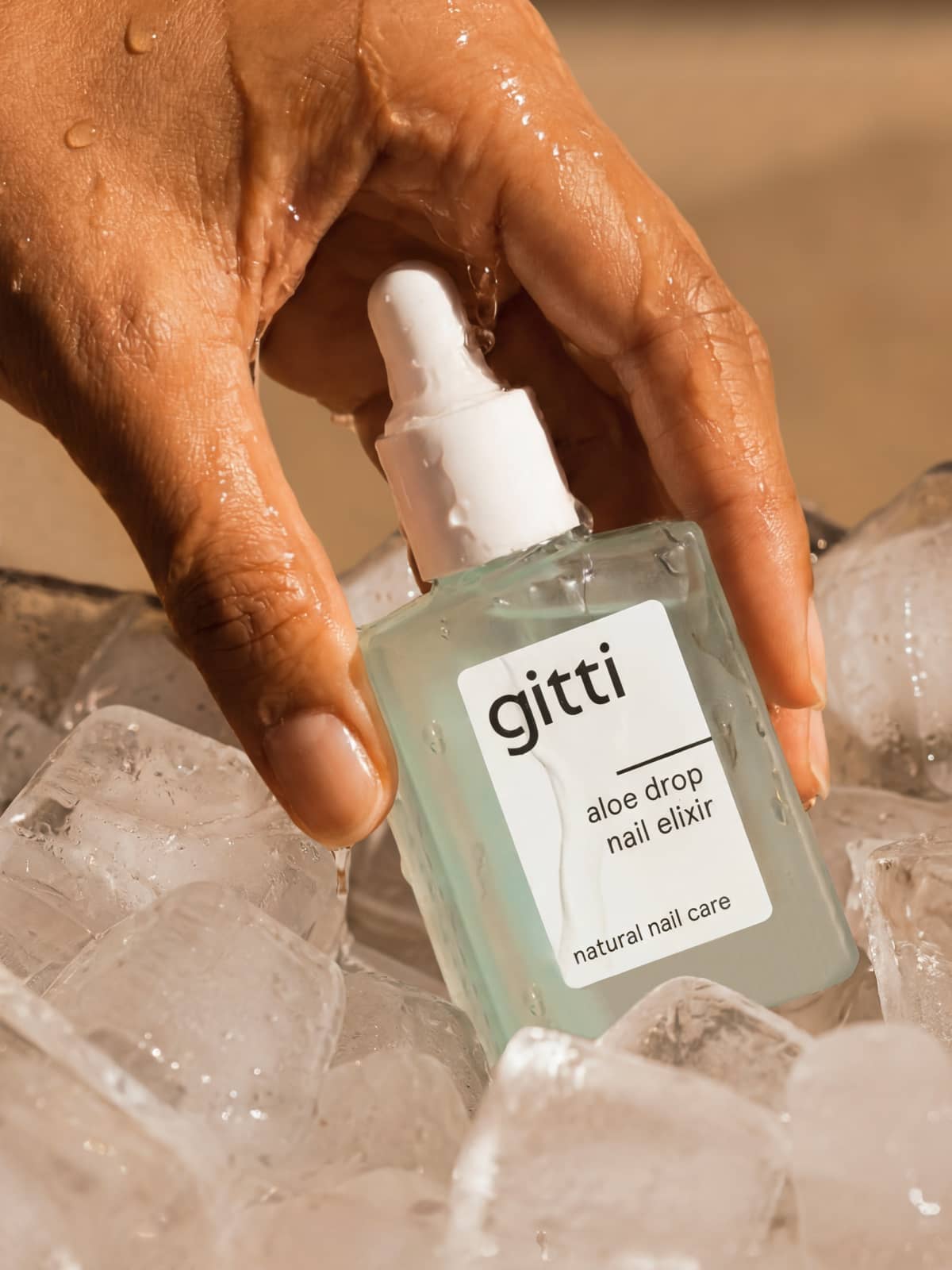 Eine Hand, die eine Flasche aus dem „Colour & Concentrate Trio“ über Eiswürfeln hält; die Hand und die Flasche glänzen vor Feuchtigkeit und unterstreichen so die Frische der pflanzlichen Farbstoffe.