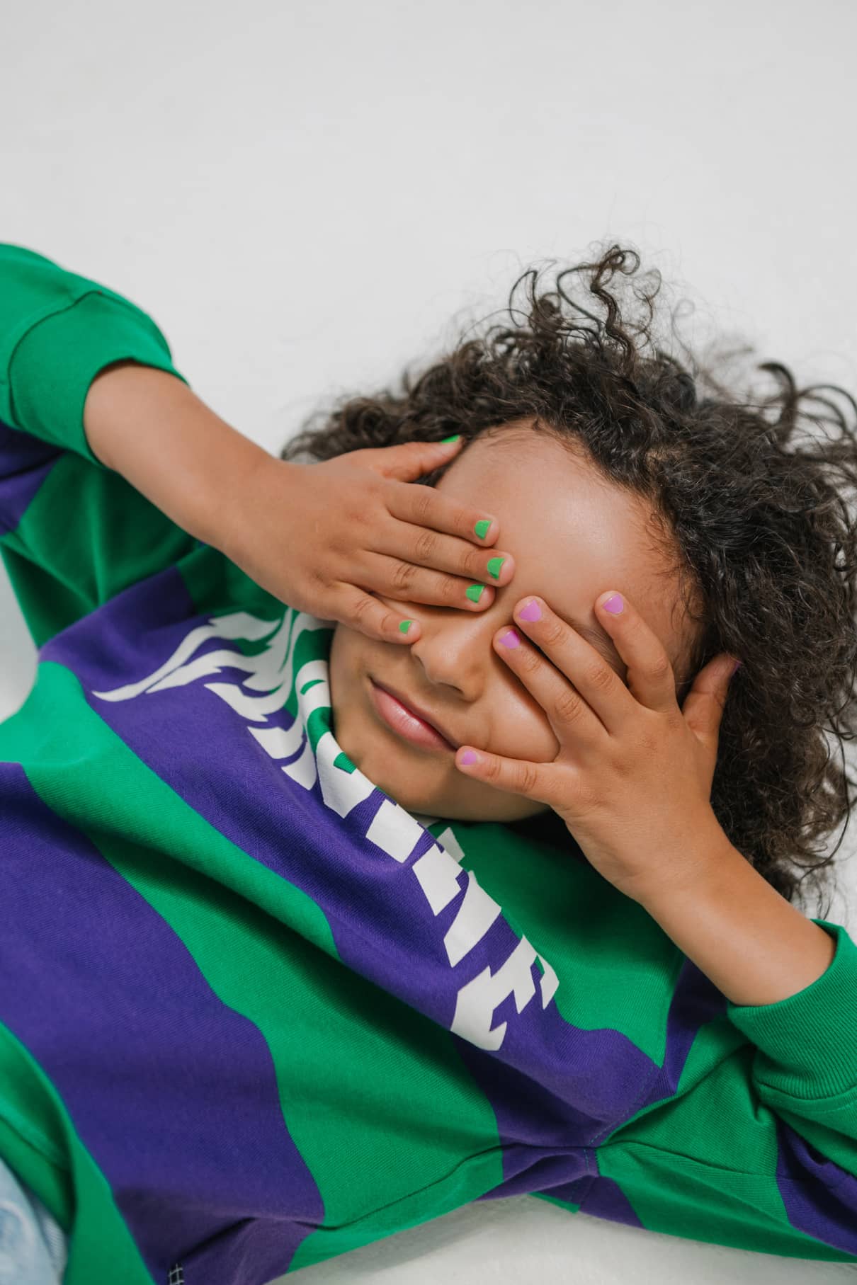 Ein Kind bedeckt seine Augen mit den Händen und zeigt die gitti kids no. 04-kinderfreundliche Nagelfarbe in hellen, verspielten Farbtönen.