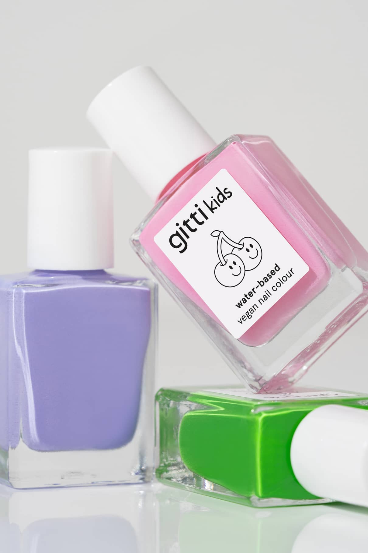 Drei Nagellackflaschen aus dem Little Artist Set - lila (La La Lilac), rosa (gitti kids, wasserbasiert, vegan) und grün - sind als Teil der verspielten Green Planet Kollektion auf einer weißen Fläche angeordnet.