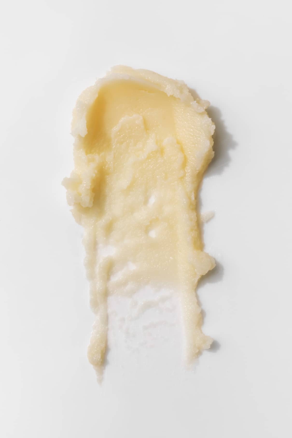 Ein Abstrich von blassgelbem Nagellackentferner-Balsam auf einer weißen Fläche.