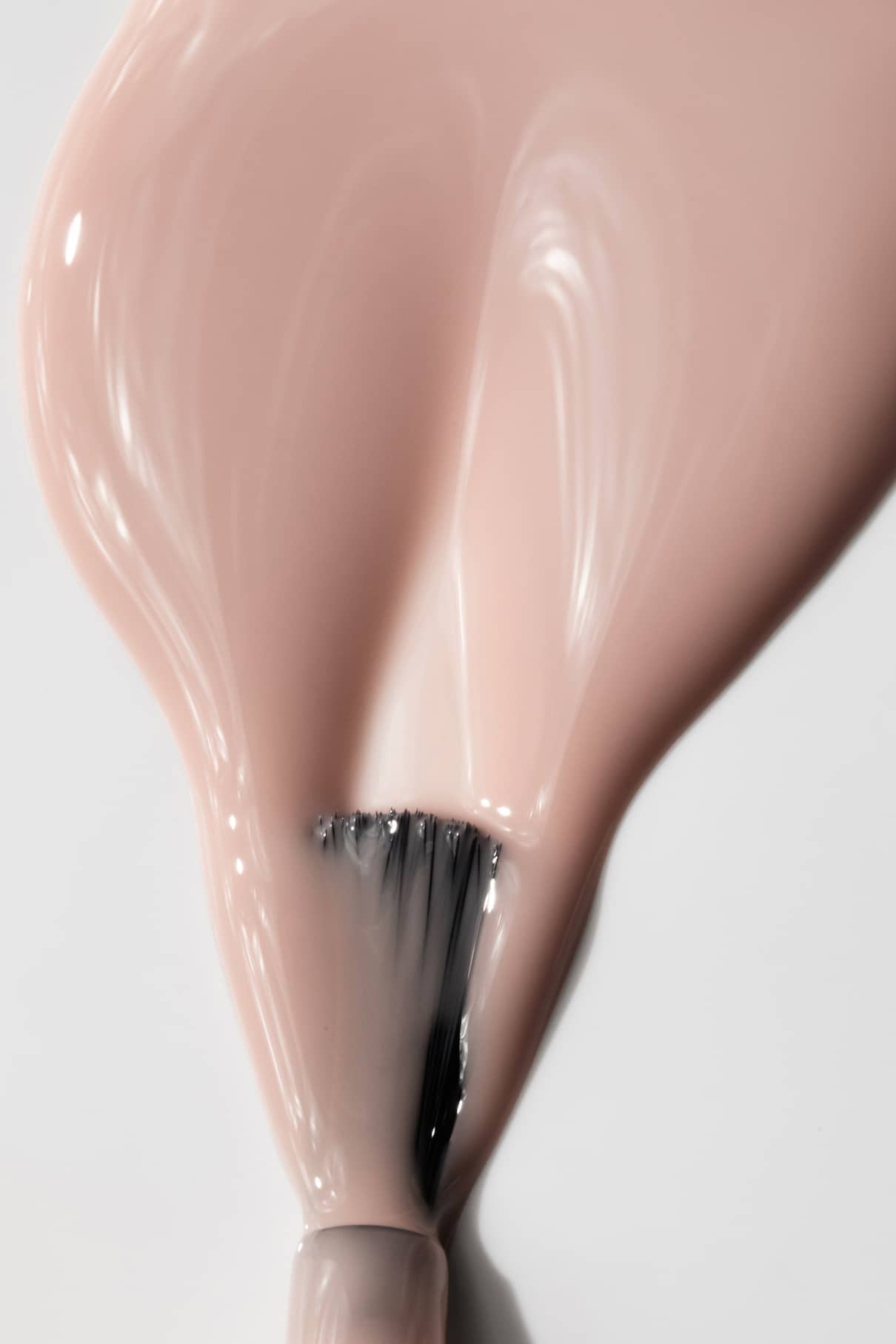 Nahaufnahme eines Pinsels, mit dem gitti no. 001, ein glänzender beiger Nagellack, in einer glatten Schicht auf eine weiße Oberfläche aufzutragen, wobei die Eleganz des glänzenden Beigetons hervorgehoben wird.