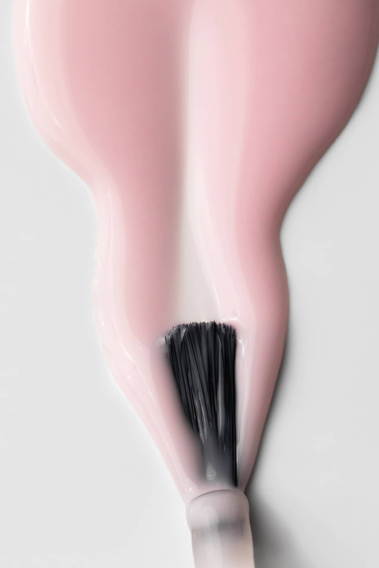 Nahaufnahme eines Nagellackpinsels, mit dem gitti no. 003, einem blassrosa Farbton, wobei die Farbe auf einer weißen Fläche verteilt wird.