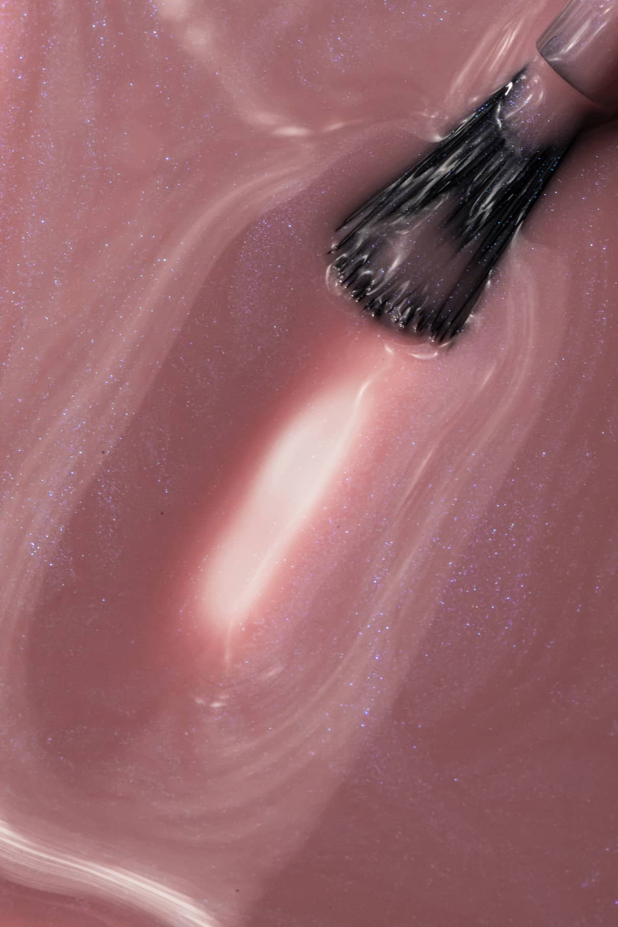 Nahaufnahme eines Pinsels, mit dem gitti no. 004, ein schimmernder rosa-mauvefarbener Nagellack mit sichtbaren Wirbelmustern und einer glänzenden Textur.