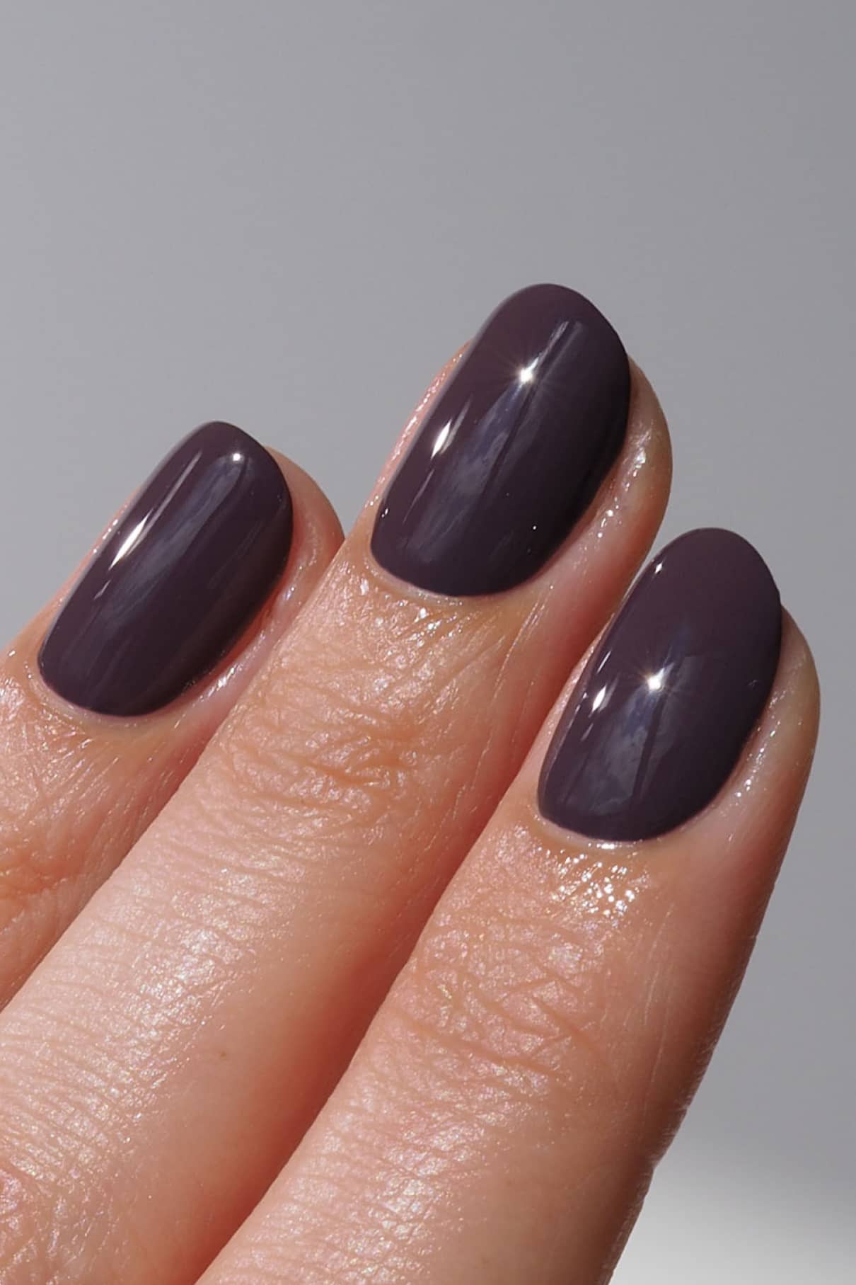 Close up of three glossy dark purple nails painted with gitti no. 012 vegan nail color.