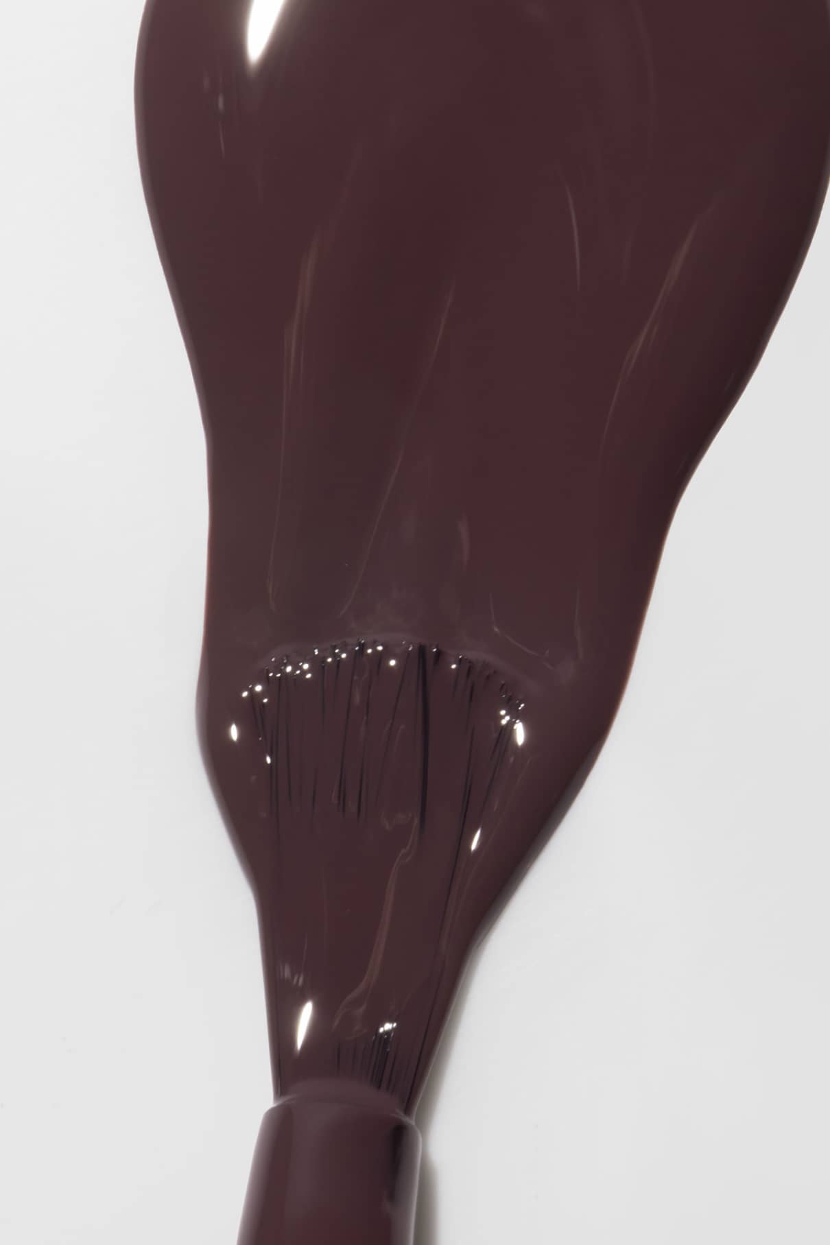 Nail polish brush coated with deep plum color ready for application
