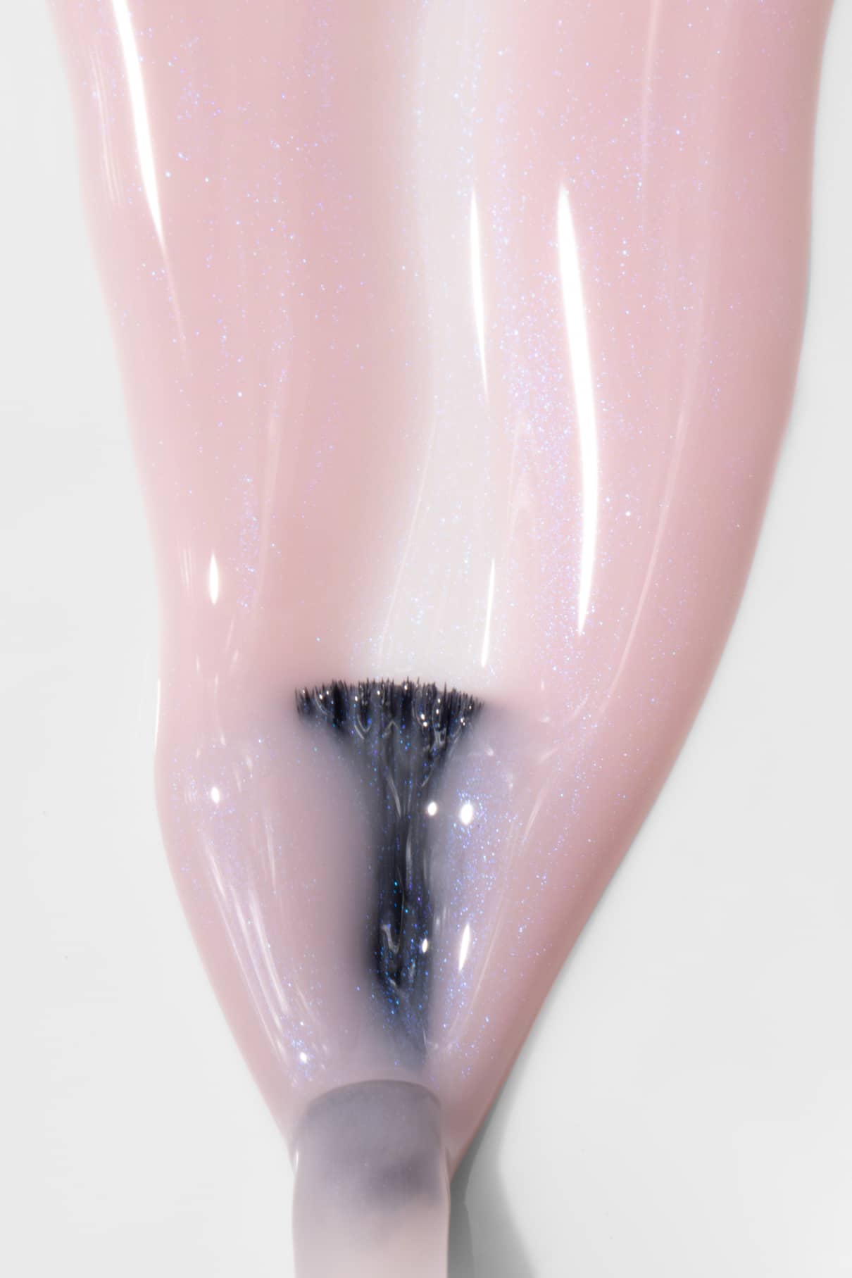 Nahaufnahme eines Pinsels, mit dem gitti no. 025, ein halbtransparenter rosa Nagellack mit bläulichem Schimmer, auf einen Fingernagel.