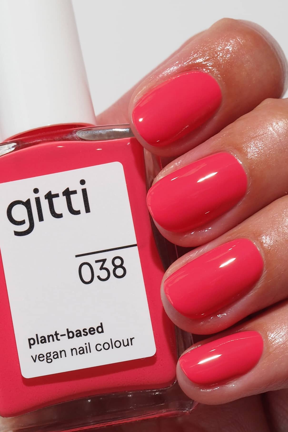 Eine Hand mit sauber manikürten, in leuchtendem Pink lackierten Nägeln hält einen Flakon aus der Plant Collection, der sich perfekt mit unseren pflegenden Base Coats kombinieren lässt und für ein makelloses Finish sorgt.