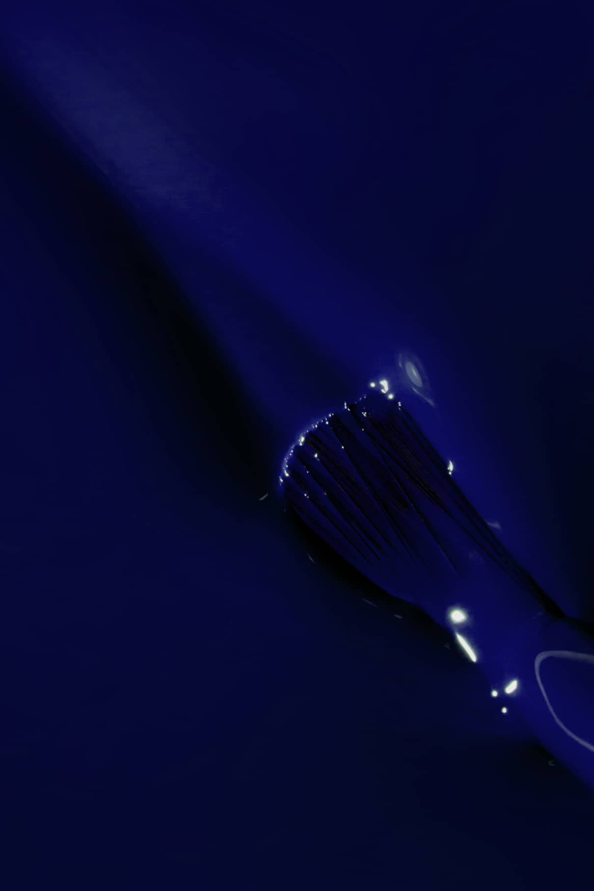 Ein Pinsel trägt gitti no. 108 auf eine glatte Oberfläche, wobei Lichtreflexe das intensive Blau der glänzenden Farbe verstärken.