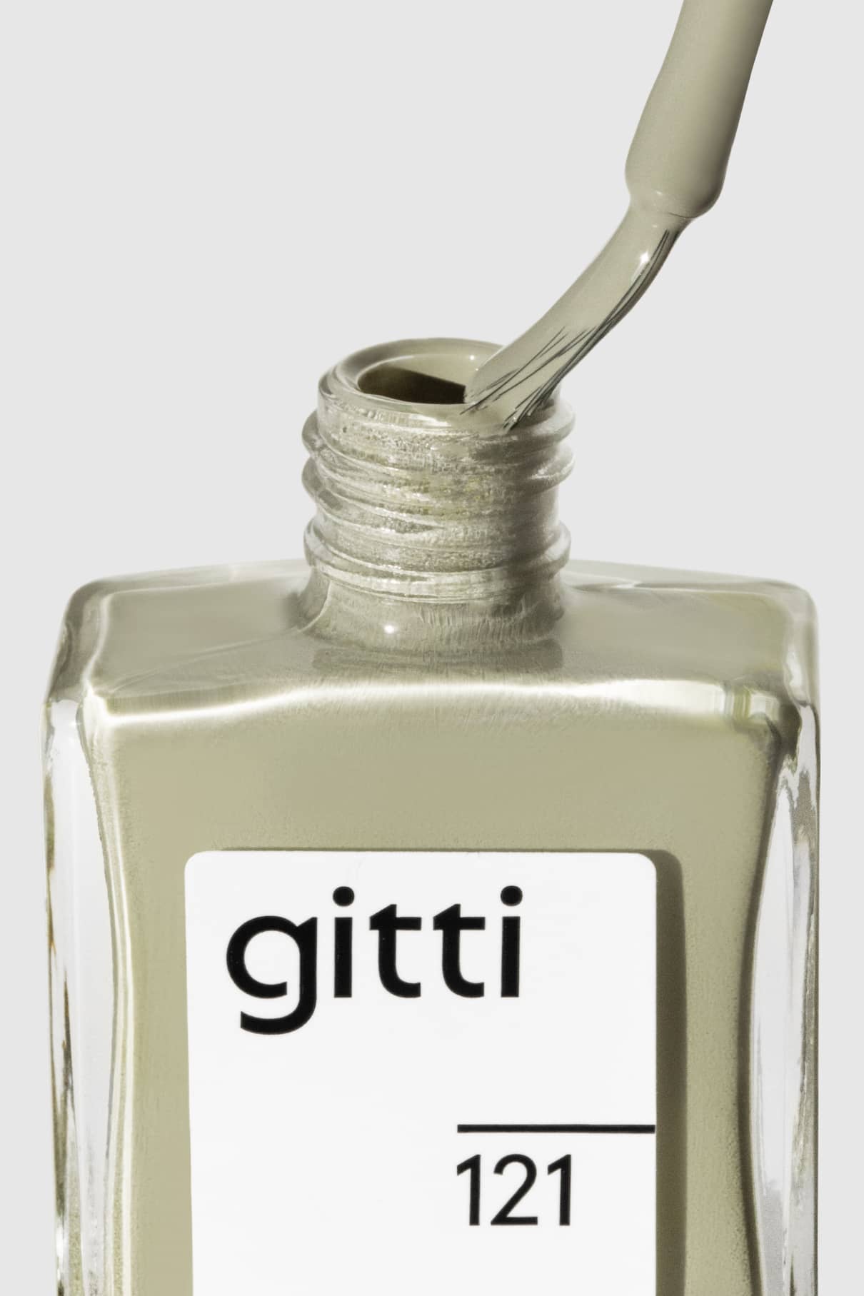 Eine Nahaufnahme einer geöffneten Flasche gitti no. 121 Nagellack, wobei der Pinsel entfernt und mit einem zarten Grün überzogen wird, das an Salbei-Wandfarbe erinnert.