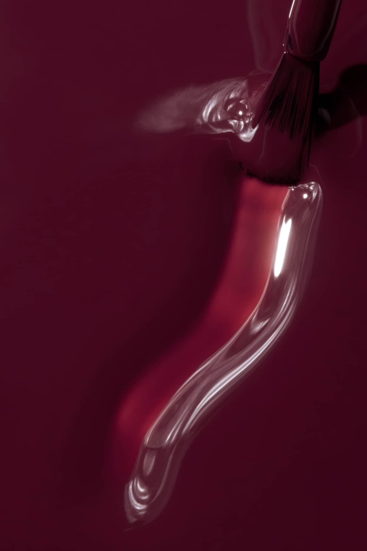 Nahaufnahme eines Pinsels, mit dem gitti no. 127 Nagellack in der Farbe Beerenpflaume, der eine glatte, glänzende Oberfläche mit sichtbaren Reflexen erzeugt.