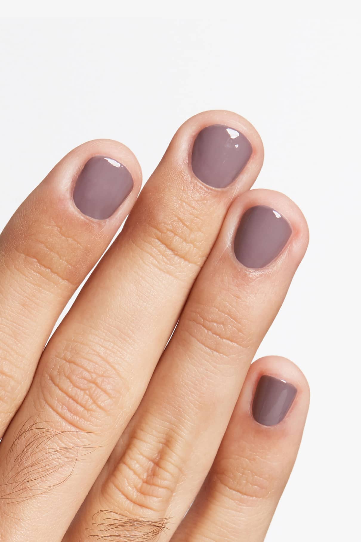 Eine Hand mit kurzen, sauber gefeilten Nägeln, lackiert in glänzendem gitti no. 129 Grau-Violett taupe vor einem weißen Hintergrund für einen eleganten, modernen Look.