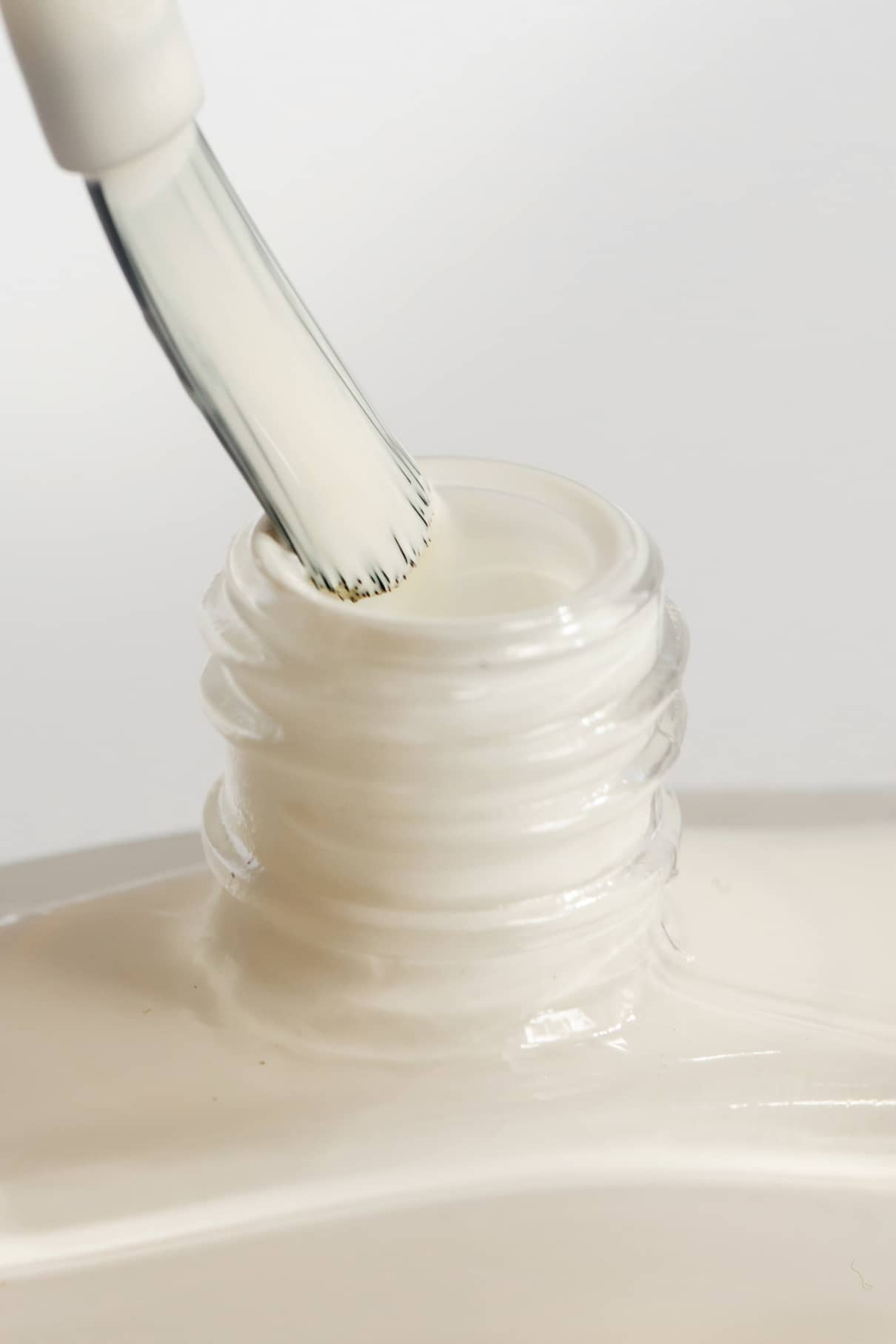 Nahaufnahme eines Pinsels, der in eine Flasche mit gitti no. 157, einem cremeweißen Nagellack mit einem cremefarbenen Finish.