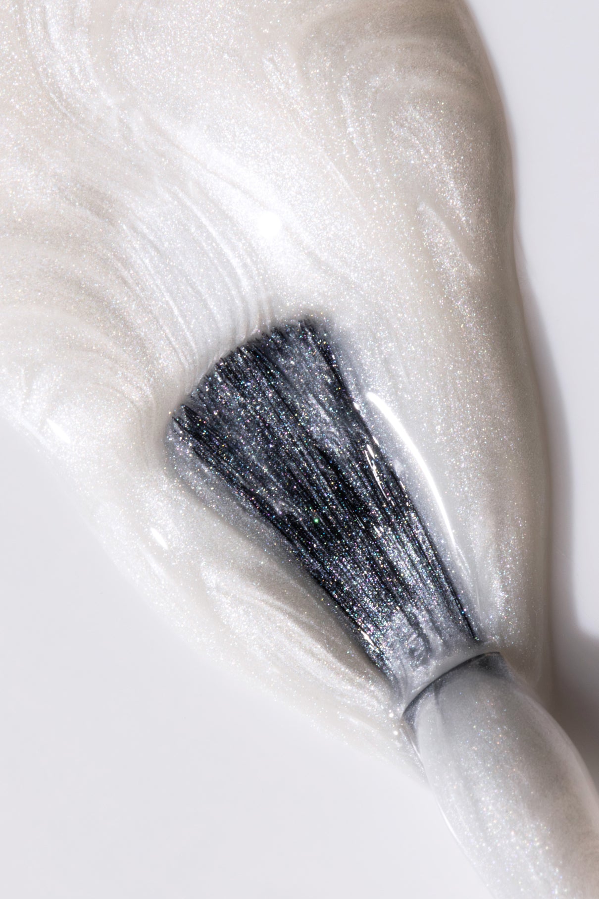 Nahaufnahme eines Nagellackpinsels beim Auftragen von gitti no. 313, ein weißer Perlglanzlack mit wirbelnder Textur und schimmerndem Finish - ideal für den Pearl Nails Trend-Look.