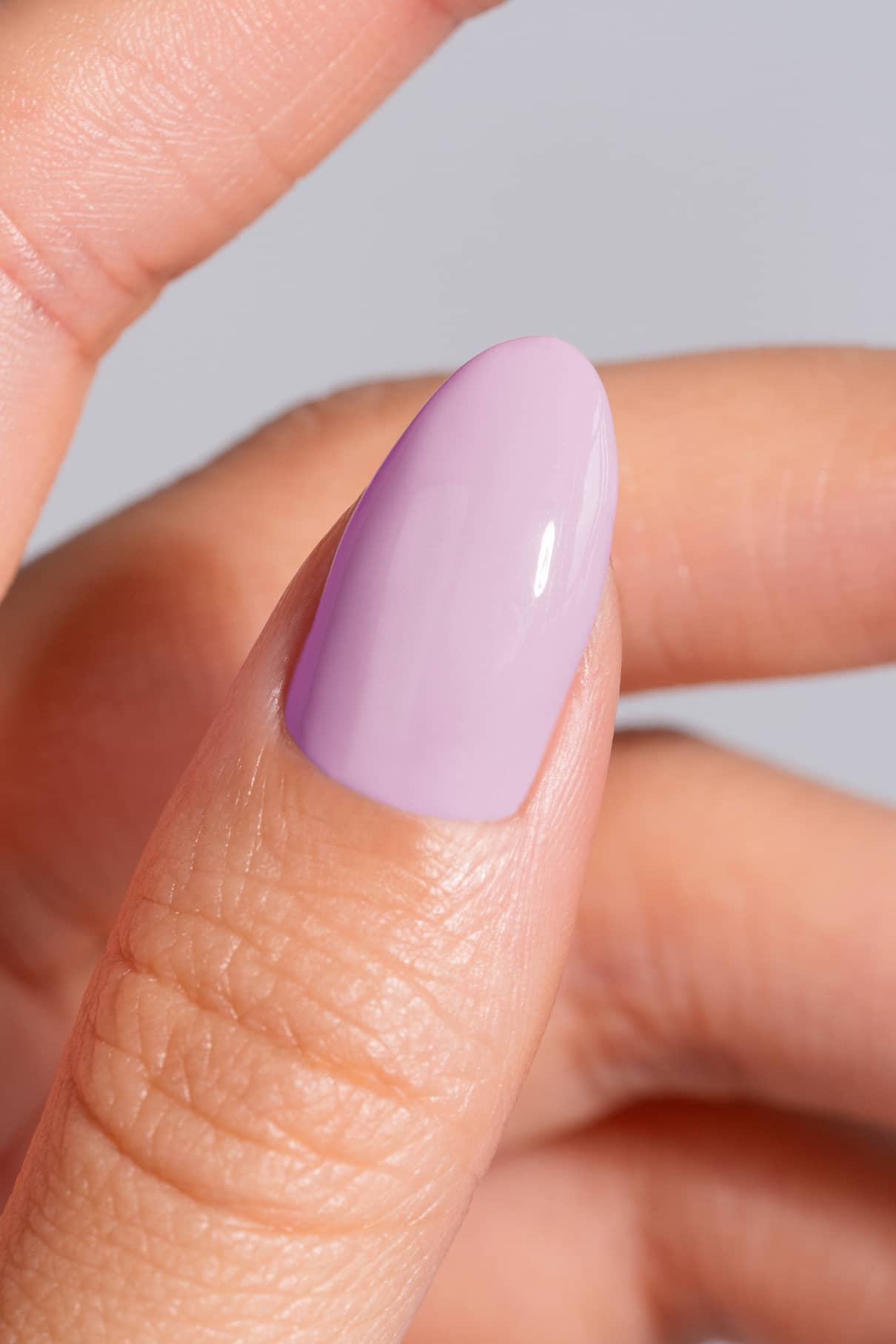 Nahaufnahme einer Hand mit einem Daumen, der mit einem glänzenden, pastellfarbenen lila Nagellack in gitti no. 03+, der einem wärmeren Unterton schmeichelt.