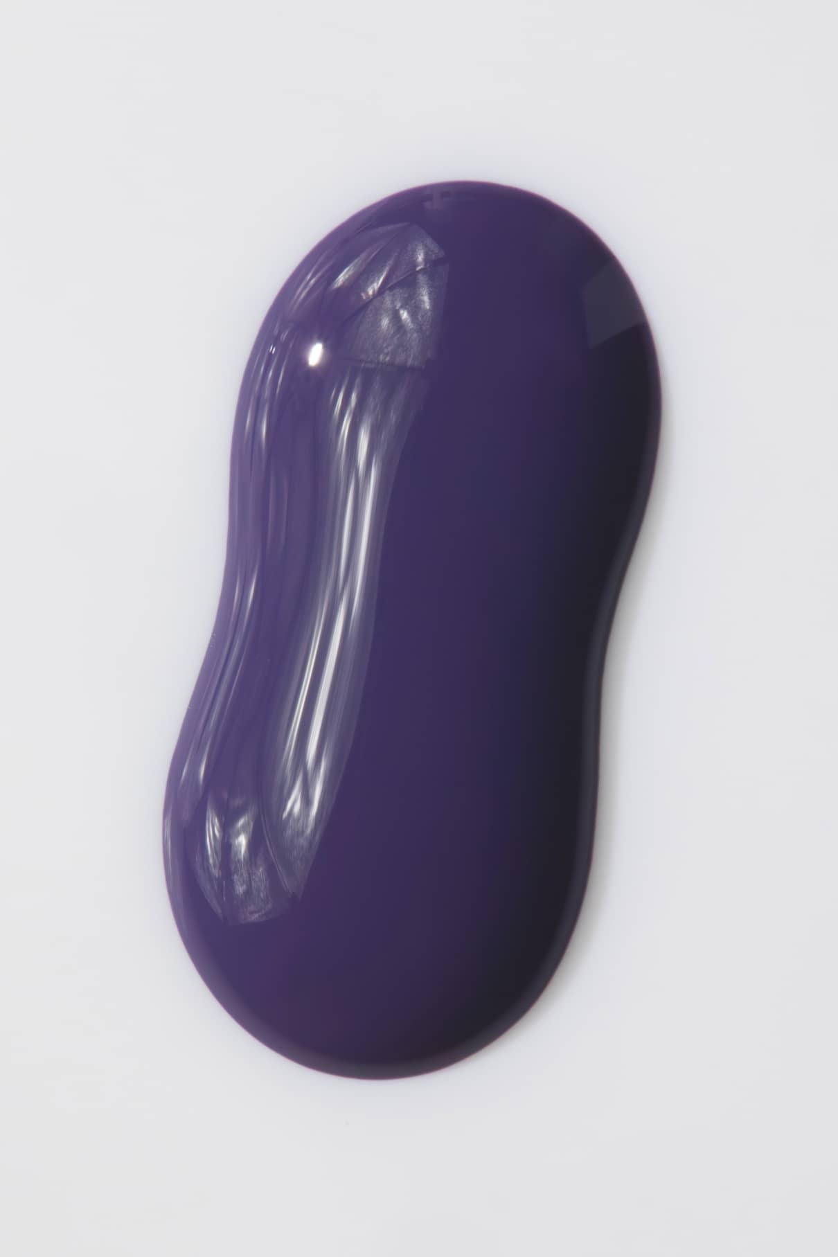 Ein glatter, glänzender Klecks von gitti no. 07+ mit einem dunkelvioletten Farbton mit lila Unterton und geschwungenen Rändern ruht auf einem schlichten weißen Hintergrund.
