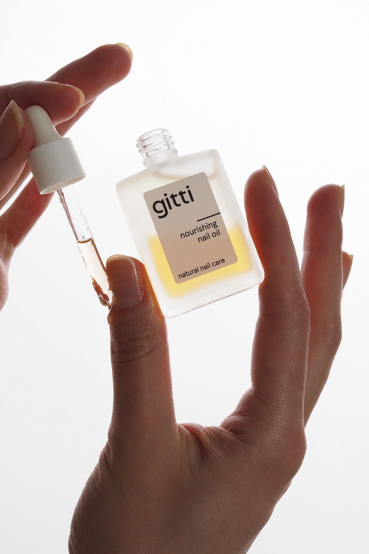 Eine Hand hält eine Flasche Nail Recovery Starter Treatment, während die andere mit einer Pipette das Öl entnimmt - perfekt für Ihre Reparaturroutine und stärkere Nägel.