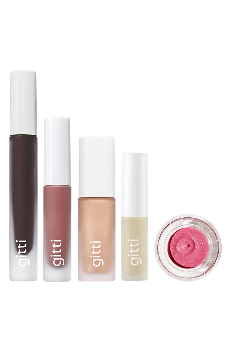 Fünf Gritti Signature Set Make-up-Produkte sind nebeneinander auf einem weißen Hintergrund angeordnet, darunter Lip Glaze, Mascara in Tuben, ein Flakon und ein kleiner Tiegel mit rosa Creme für eine einfache Brow Control.