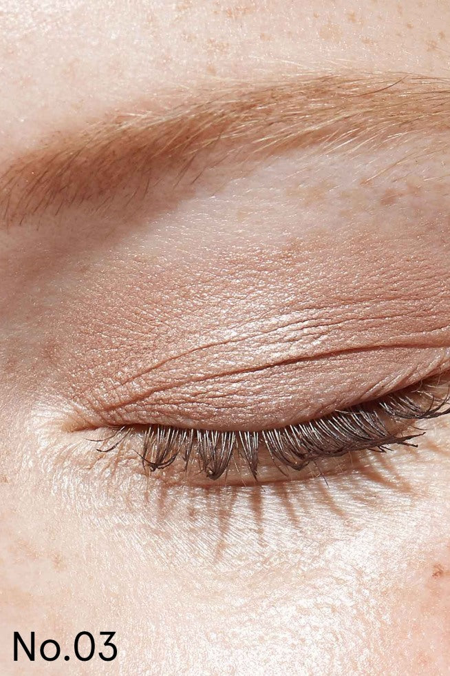 Nahaufnahme eines geschlossenen Auges mit hellbraunem Lash, Lip & Cheek Trio auf dem Lid und den natürlichen Wimpern, Hervorhebung der Augenbraue und der Hauttextur; Nr. 03 erscheint in der unteren linken Ecke.