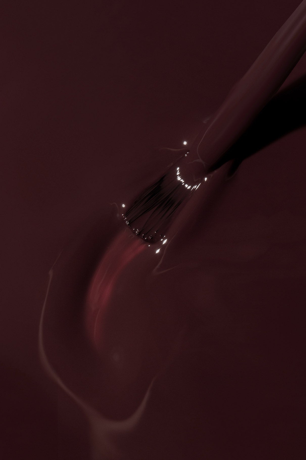 Eine Nahaufnahme eines Pinsels, mit dem gitti no. 183 Nagellack aufzutragen, wobei glänzende Reflexe auf der farbenprächtigen Oberfläche sichtbar werden.
