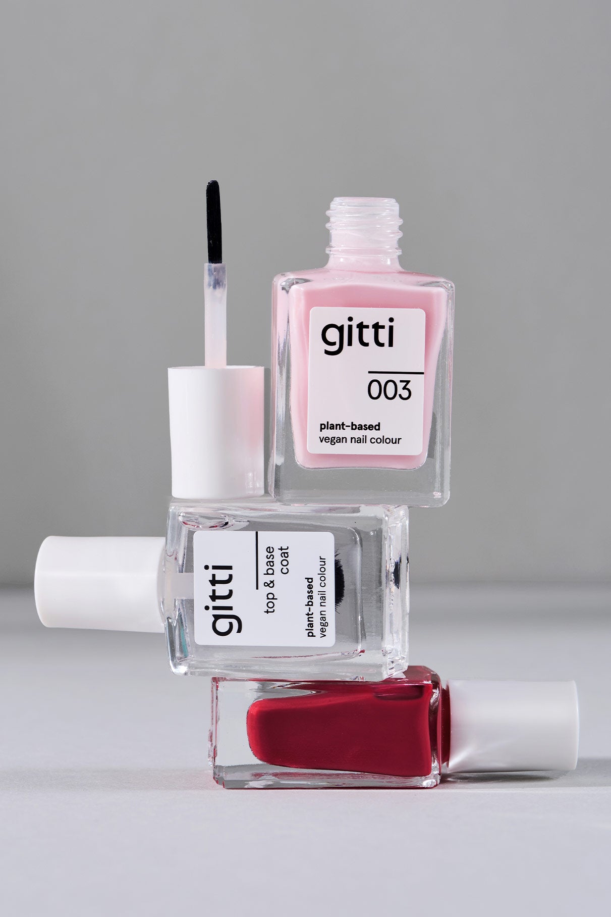 Drei Mini Getaway Set-Fläschchen sind gestapelt, eine davon offen mit dem Pinsel, der pinke und rote Farbtöne sowie einen klaren Top & Base Coat zeigt - ideal, um Ihr eigenes Reiseset zusammenzustellen.