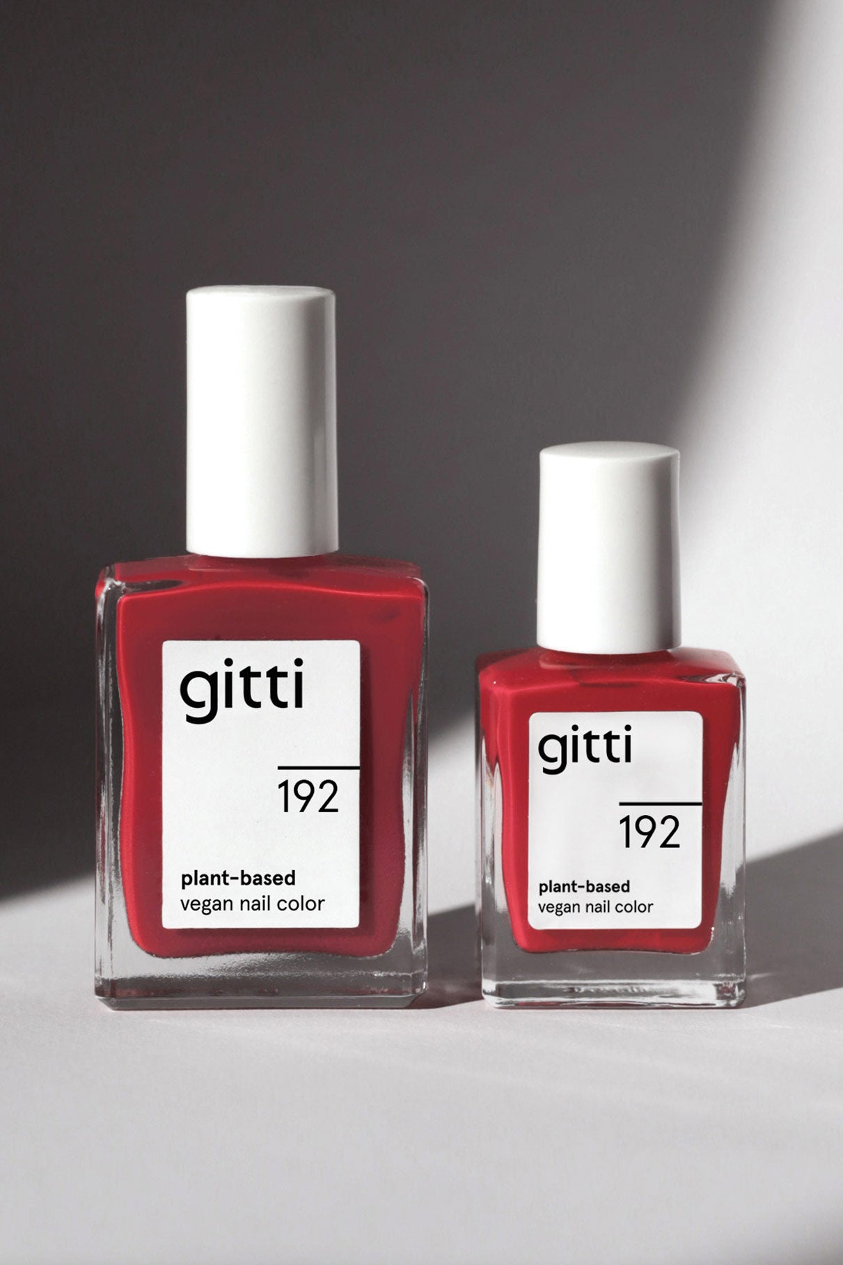Zwei Fläschchen aus dem Mini Getaway Set mit der pflanzlichen veganen Nagelfarbe Gitti in der Farbe 192 stehen nebeneinander auf einer hellen Fläche, die von natürlichem Licht beleuchtet wird - perfekt für Ihre nächste Reise.