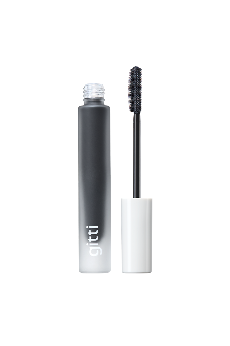 Die schwarze Infinite Lash Wimperntusche mit weißer Kappe steht aufrecht neben ihrem feinen Borsten-Bürsten-Applikator. Die demi-matte Formel sorgt für Definition und Länge. Das Röhrchen trägt die Aufschrift gitti.