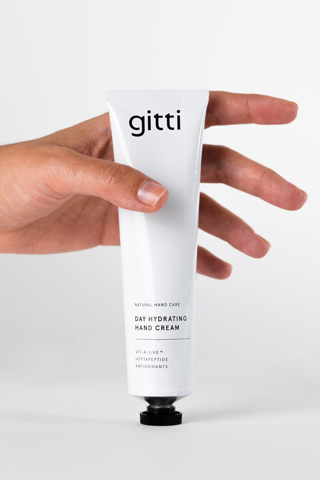 Eine Hand hält eine Tube der Day Hydrating Hand Cream, ideal für die tägliche Handpflege, vor einem schlichten weißen Hintergrund.