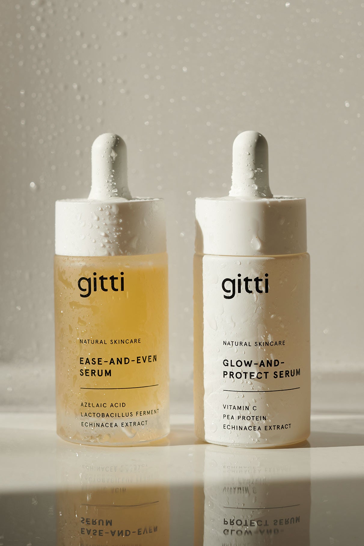 Das Serum Duo von gitti skincare, bestehend aus dem Ease-and-Even Serum und dem Glow-and-Protect Serum, wird nebeneinander auf einer feuchten Oberfläche im Sonnenlicht präsentiert.